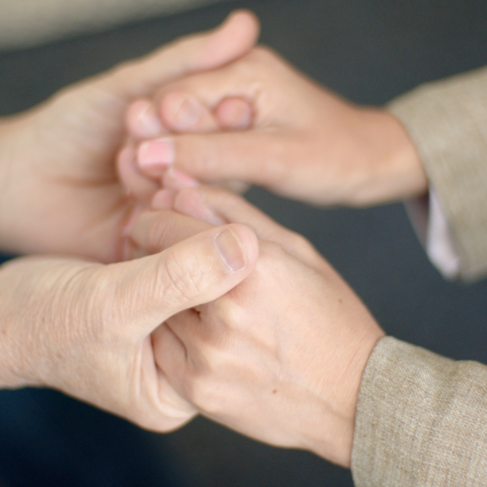 Two individuals holding hands in a comforting gesture.